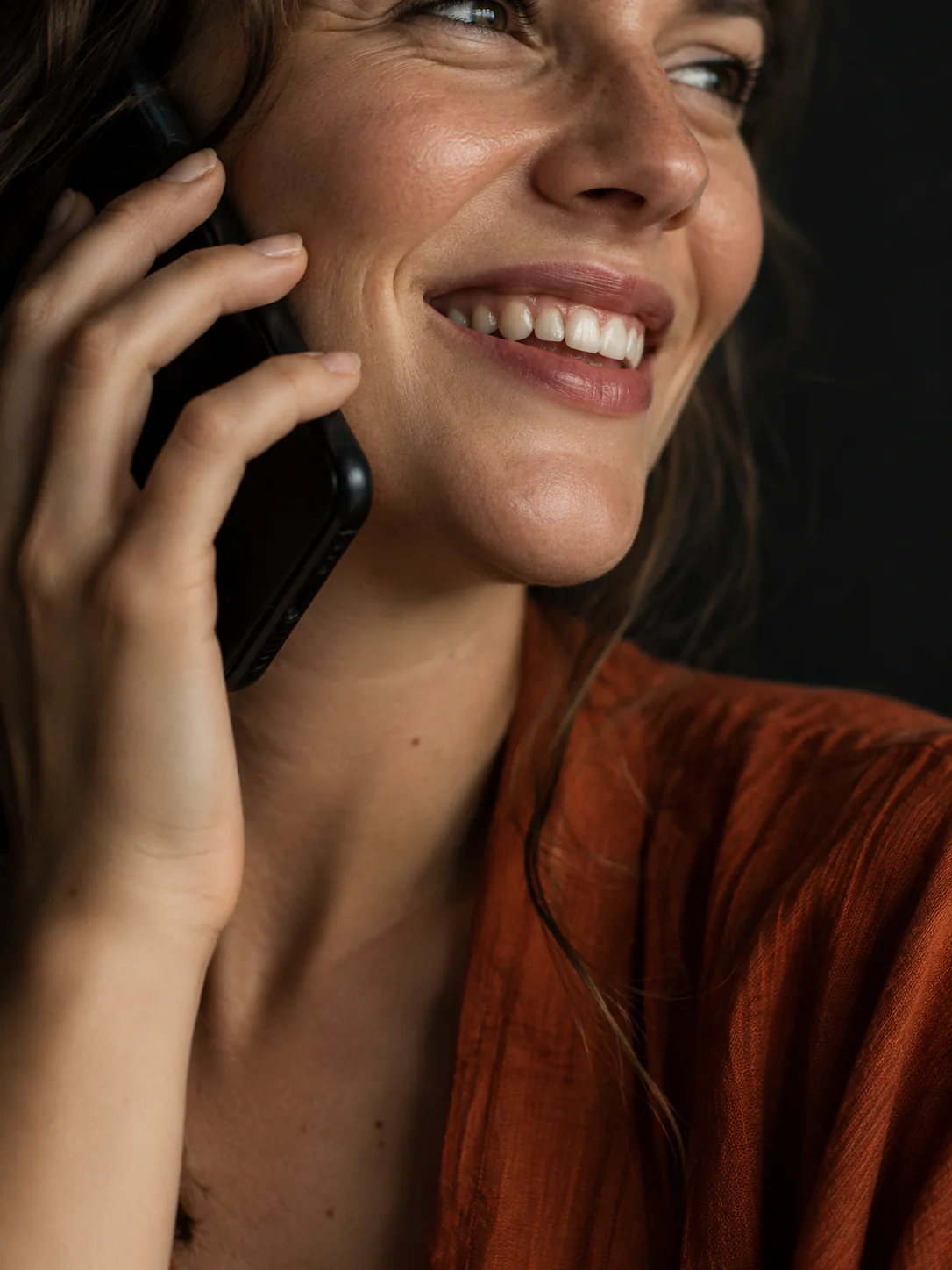 A white woman smiling warmly during a voice conversation.